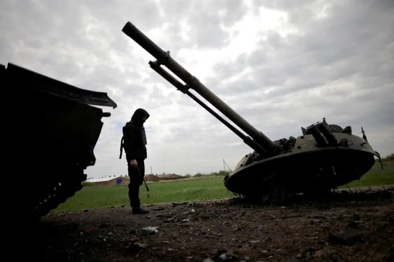 Một quân nhân Ukraine kiểm tra một chiếc xe bọc thép bị phá hủy của Nga ở vùng Zaporizhzhia, Ukraine. Ảnh: REUTERS