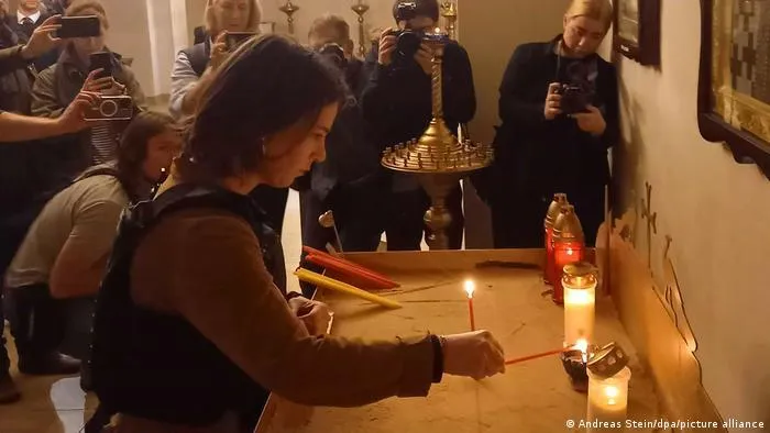 Ngoại trưởng Đức Annalena Baerbock thắp nến tưởng nhớ các nạn nhân trong một nhà thờ ở Bucha. Ảnh: DPA