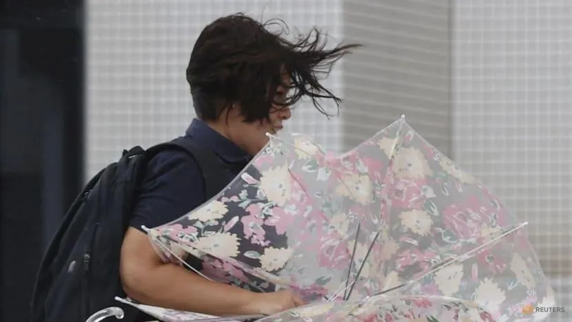 Một người phụ nữ băng qua đường trong gió mạnh do bão Hinnamnor ở Naha, tỉnh Okinawa (Nhật Bản) ngày 4-9. Ảnh: REUTERS