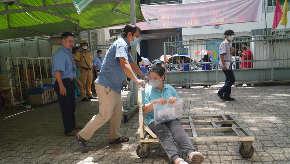 Cán bộ coi thi dùng xe đẩy em đến cầu thang và hỗ trợ dìu Nhi lên tận phòng thi.