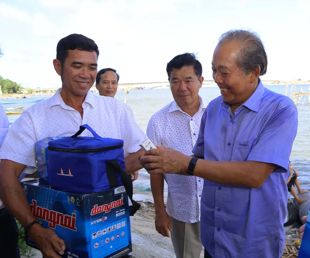 Tại nhà ngư dân Lê Gia Huy (43 tuổi), đoàn chia sẻ với hoàn cảnh &quot;gà trống&quot; nuôi bốn con nhỏ của ông khi người vợ vừa mất đầu năm 2023 do ung thư. Bằng ý chí can trường của ngư dân miền biển, ông vẫn miệt mài bám biển, nỗ lực nuôi con, thoát nghèo. Trong ảnh: Ngư dân Lê Gia Huy nhận dầu gió từ nguyên Phó Thủ tướng thường trực Chính phủ Trương Hòa Bình và quà từ chương trình và. Ảnh: HOÀNG GIANG
