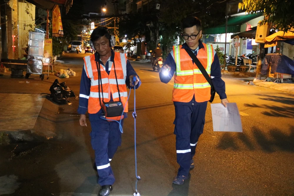 Công nhân vừa di chuyển, vừa đeo thiết bị dò tìm đường ống nước bể. Công nhân vừa di chuyển, vừa đeo thiết bị dò tìm đường ống nước bể.