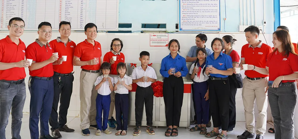 Đại diện Dai-ichi Life Việt Nam cùng nhà trường và các em học sinh thưởng thức nguồn nước uống sạch từ hệ thống máy vừa được trao tặng.
