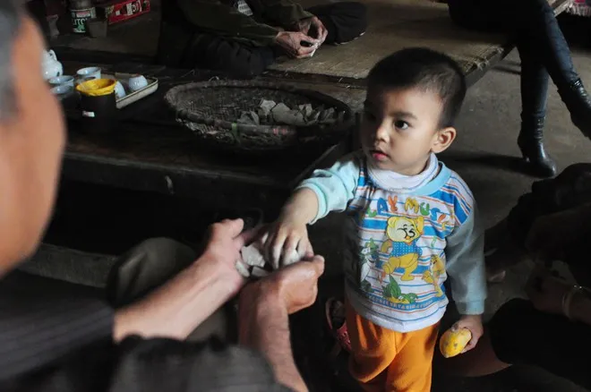 Trong ảnh, cháu Khổng Tuấn Hưng lấy "ngói" cho ông nội Khổng Văn Lộc (59 tuổi), con trai cả bà Biện cùng với các cụ trong nhà ăn. Ông Đỗ Văn Bình – Trưởng thôn Thống Nhất, thị trấn Lập Thạch cho biết: “Tục ăn đất đã có từ nhiều đời ở địa phương. Trước đây không chỉ dân Lập Thạch ăn mà còn nhiều người ở các huyện, tỉnh lân cận cũng về mua về làm quà. Ngày nay, không còn tục đó nữa chỉ còn một, hai cụ cao niên trong thôn còn ăn như cụ Biện, cụ Loa, bà Huệ”.