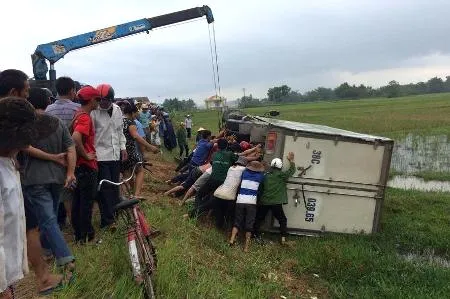 Người dân cùng cơ quan chức năng nỗ lực đưa chiếc xe lên khỏi cánh đồng