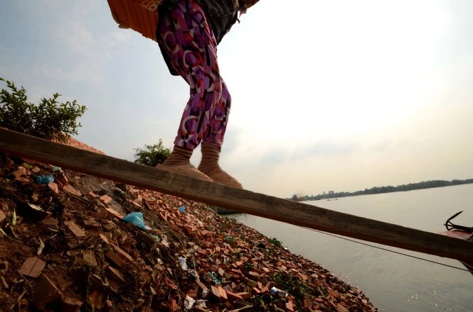 Bước chân chông chênh của các chị trên cầu tạm đưa gạch xuống ghe - Ảnh: Thanh Tùng Bước chân chông chênh của các chị trên cầu tạm đưa gạch xuống ghe - Ảnh: Thanh Tùng