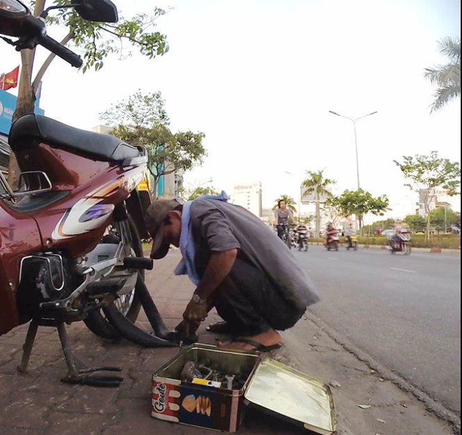 Phong dùng cây cạy ấn mạnh vào chân van ruột xe tạo ra vết rách, ép khách phải thay ruột (ảnh chụp chiều 1-4-2015 tại giao lộ Điện Biên Phủ - Đinh Bộ Lĩnh, Q.Bình Thạnh) - Ảnh: Đình Khánh