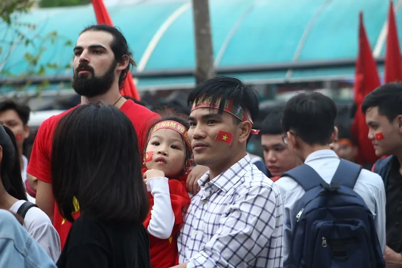 Các em nhỏ cùng bố mẹ chăm chú theo dõi trận đấu.