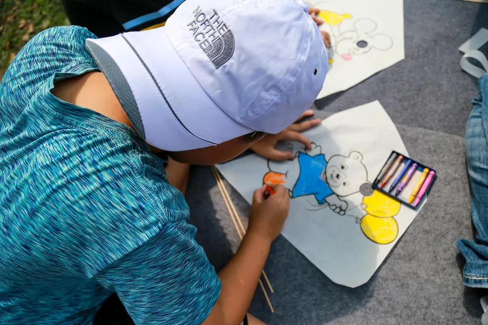 Một em nhỏ trải nghiệm làm diều tại Lễ hội diều Huế.