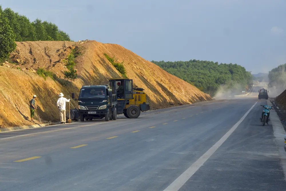 Để chuẩn bị cho ngày thông xe, các công nhân tiến hành dọn vệ sinh dọc tuyến. Ảnh: NGUYỄN DO