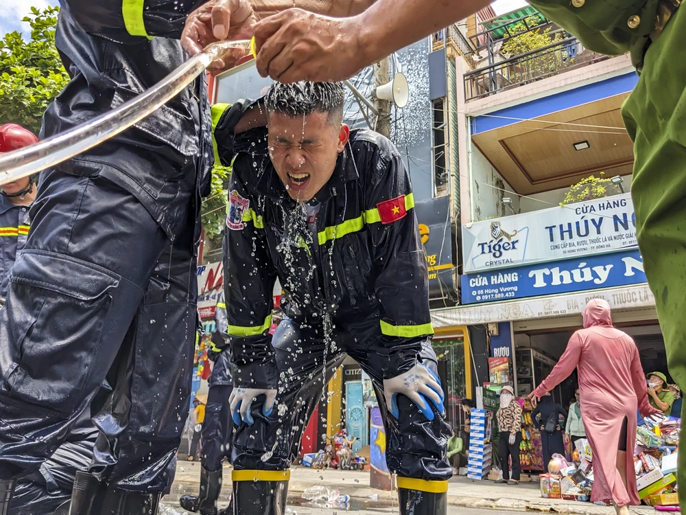 Nắng nóng nên các chiến sĩ phải dội nước làm mát cơ thể khi vào tiếp cận đám cháy. Ảnh: ND