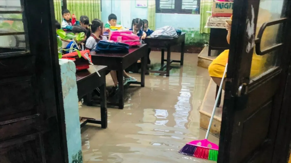 Giáo viên dùng chổi đẩy nước và bùn đất ra ngoài. Ảnh: T.P hoc-sinh-nghi-hoc (4).jpg