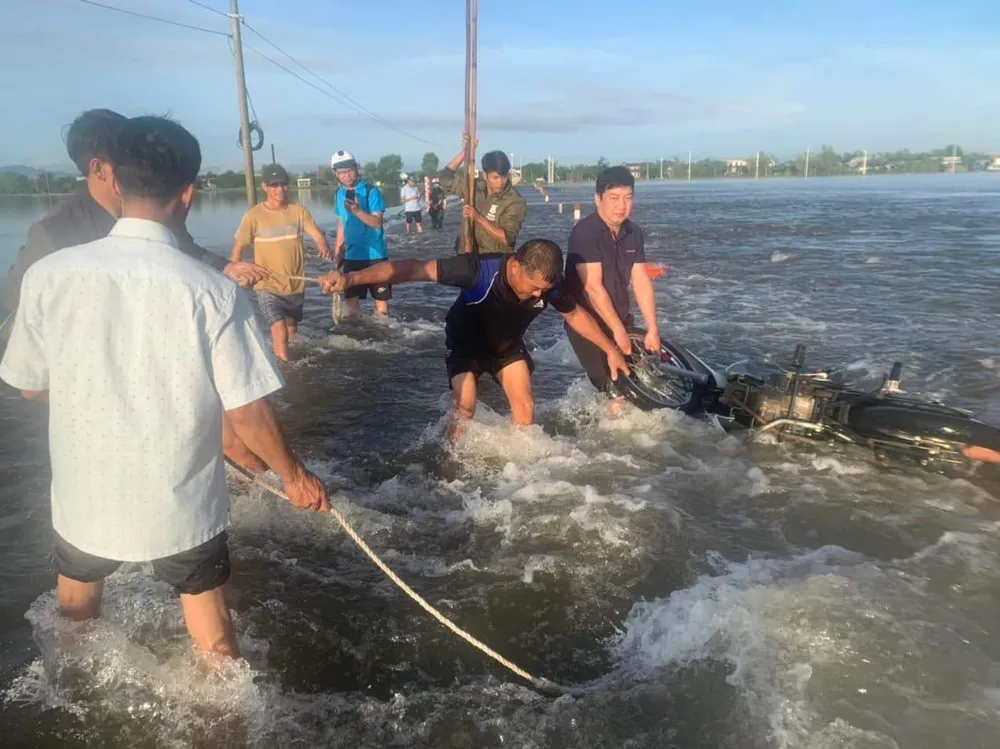 Lực lượng chức năng và người dân kéo chiếc xe máy lên đường. Ảnh: BT Cứu vợ chồng bị nước cuốn trôi