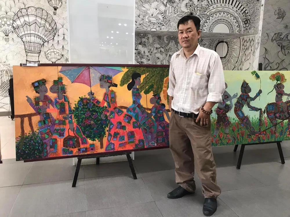 Hoạ sĩ Văn Thạnh bên cạnh tác phẩm &quot;Hội quê&quot; của mình. Ảnh: Ái Phương