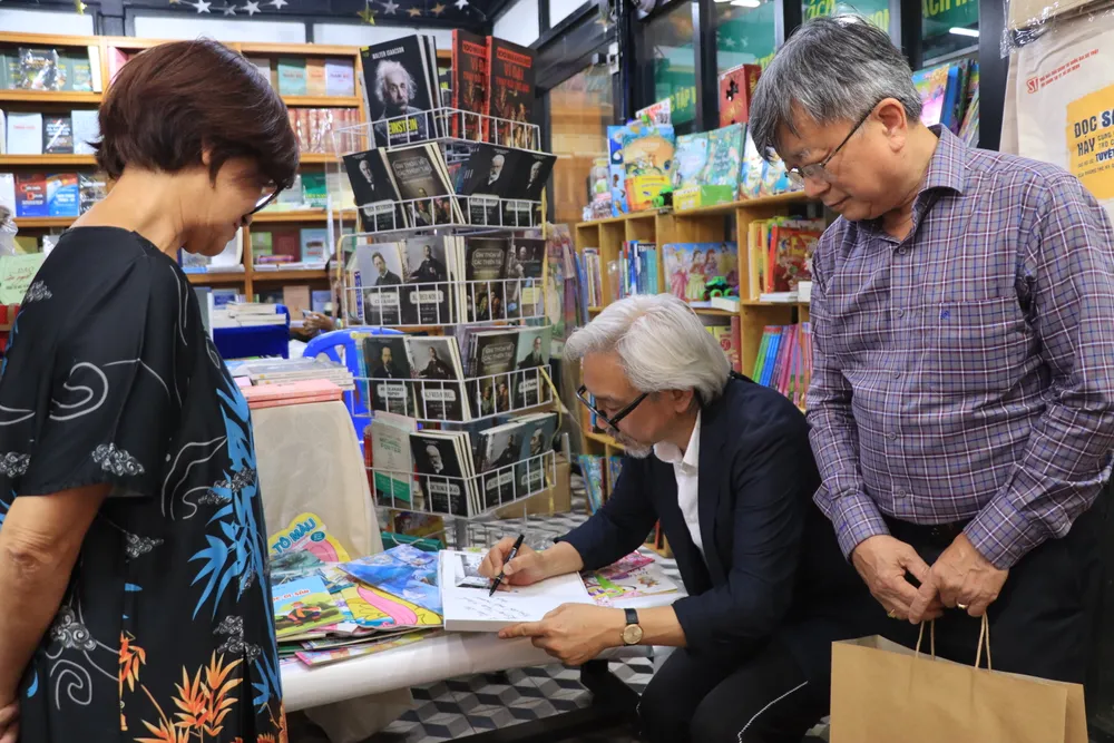 Nhiếp ảnh gia Dương Minh Long ký tặng cho khán giả. Ảnh: HÀ NGUYỄN