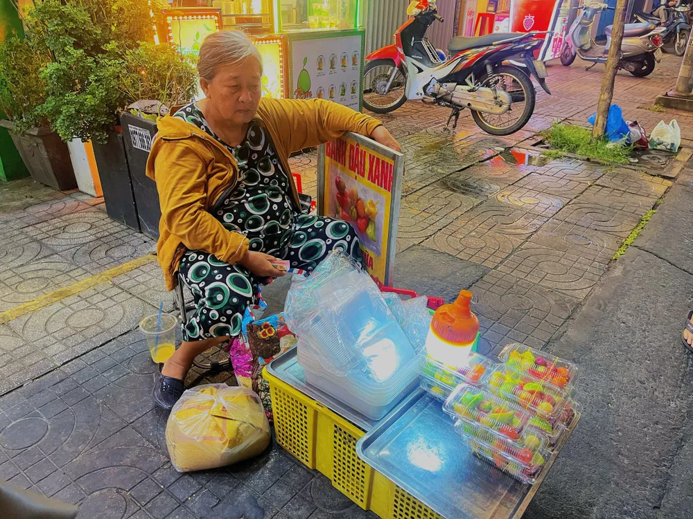 Dì Hai Bưởi bên cạnh quầy bánh trái cây đậu xanh ở góc đường Nguyễn Đình Chiểu. Ảnh: KHÁNH TRÚC Dì Hai Bưởi bên cạnh quầy bánh trái cây đậu xanh ở góc đường Nguyễn Đình Chiểu. Ảnh: KHÁNH TRÚC