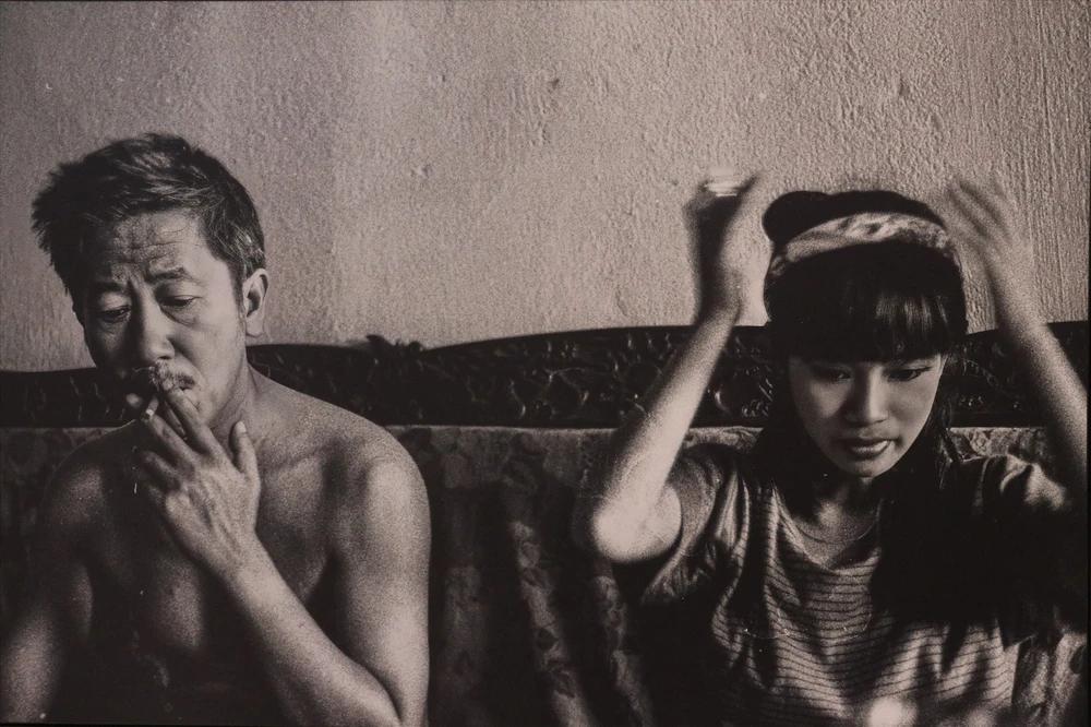 Hồng Nhung bên bố - dịch giả Lê Văn Viện. Ban đầu, nhiếp ảnh gia dự tính không đưa bức ảnh vào triển lãm vì nhân vật cởi trần, nhưng ca sĩ chủ động đề nghị vì thích sự tự nhiên, gần gũi.