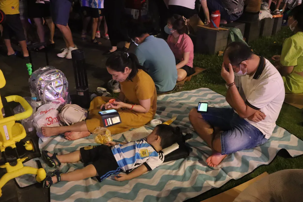 Thậm chí, người dân mang theo thảm nhựa ngồi kín bến Bạch Đằng để giữ chỗ xem pháo hoa. Ảnh: VÕ THƠ