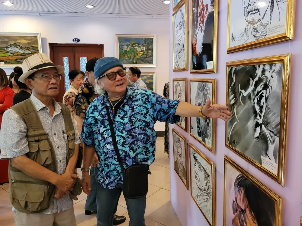 Nhiếp ảnh gia Giản Thanh Sơn và nhà báo Huỳnh Dũng Nhân tại triển lãm. Triển lãm tranh