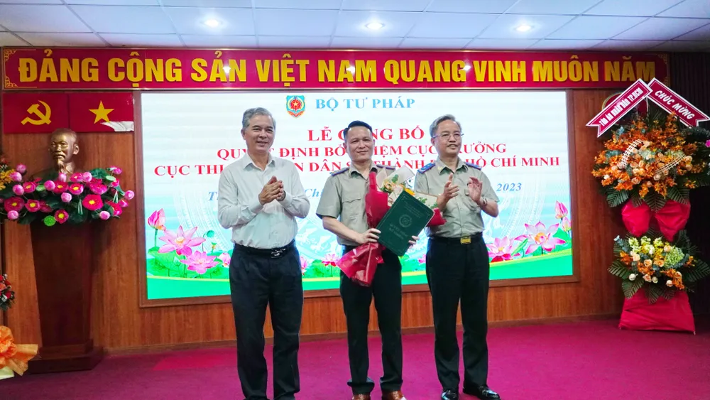 Phó Chủ tịch UBND TP.HCM Ngô Minh Châu (trái) và Tổng Cục trưởng Tổng cục THADS Nguyễn Quang Thái (phải) trao hoa và quyết định cho ông Nguyễn Văn Hòa. Ảnh: CẨM TÚ