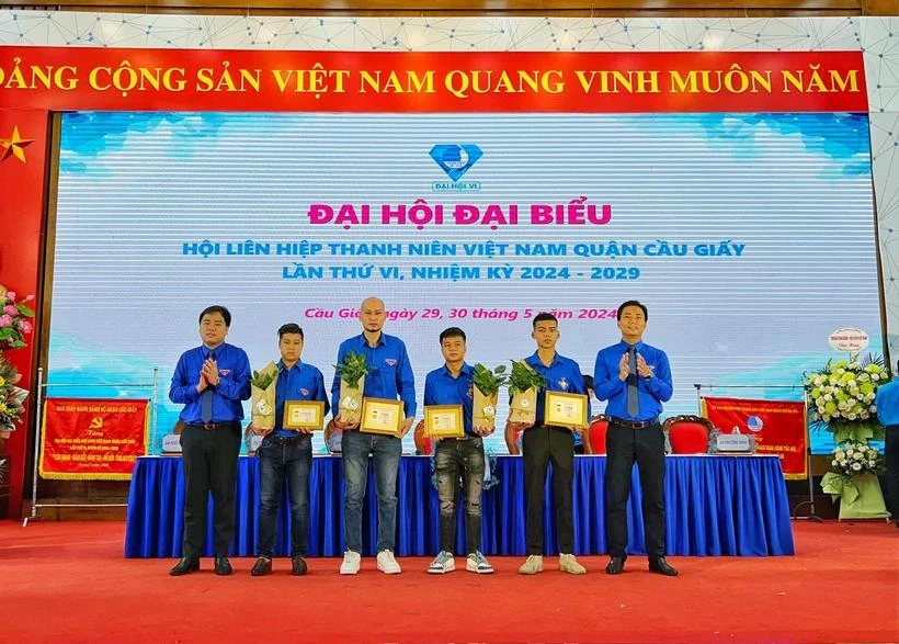 Phó Bí thư thường trực Thành đoàn TP Hà Nội Nguyễn Đức Tiến trao Huy hiệu Tuổi trẻ dũng cảm cho 4 thanh niên cứu người trong vụ cháy tại quận Cầu Giấy. Ảnh: TTXVN dung-cam.webp