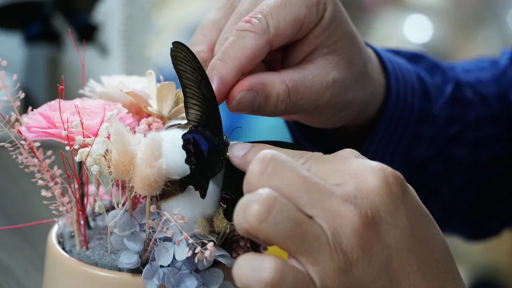 Sau khi xong thành phẩm, anh sẽ trang trí thêm những phụ kiện khác như hoa khô, bướm, lá cây... Điều đặc biệt, hiệu ứng vảy cá nở hoa sẽ xuất hiện khi được tưới nước. Ảnh: TIỂU MINH