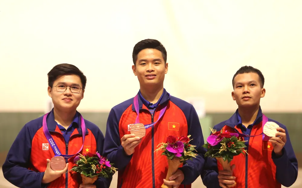 Xạ thủ Phạm Quang Huy (giữa) trên bục nhận HCĐ nội dung 10 m súng ngắn hơi đồng đội. Ảnh: QUÝ LƯỢNG hcv-pham-quang-huy-ban-sung-5.jpg