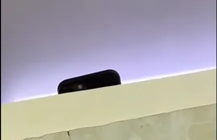 Chiếc điện thoại đang thực hiện quay lén được nam sinh quay lại khi vào nhà vệ sinh. Ảnh cắt từ clip