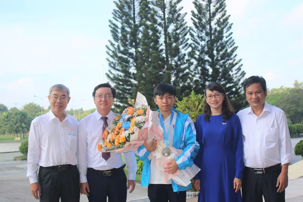 Hoàng Sơn (ôm bó hoa) chụp hình cùng các thầy cô tại buổi chào cờ đầu tuần.