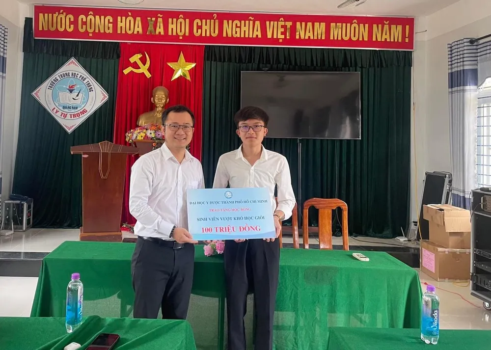 Em Lê Công Danh nhận học bổng từ phía đại diện trường trao tặng. Ảnh: TRƯƠNG ĐẠT