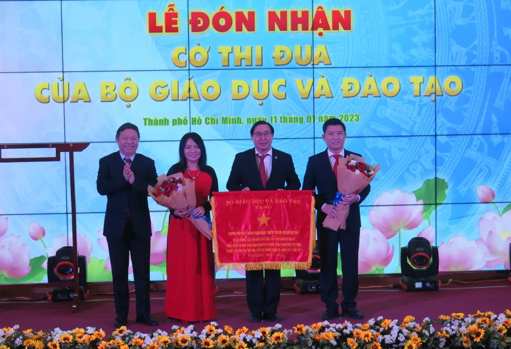 Ông Dương Anh Đức (bìa trái) trao Cờ thi đua của Bộ GD&amp;ĐT cho các đại diện lãnh đạo trường. Ảnh: PA