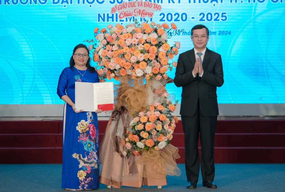Thứ trưởng Bộ GD&ĐT Nguyễn Văn Phúc trao quyết định và tặng hoa cho Tiến sĩ Trương Thị Hiền. Ảnh: NT Tân chủ tịch Hội đồng trường ĐH Sư phạm kỹ thuật TP.HCM