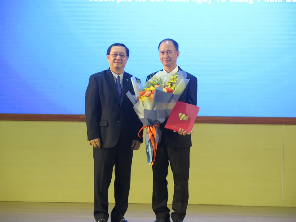 Bộ trưởng Huỳnh Thành Đạt trao quyết định bổ nhiệm và hoa cho PGS.TS Trần Cao Vinh. Ảnh: P.A dh-quoc-gia-tphcm-bo-nhiem (3).JPG