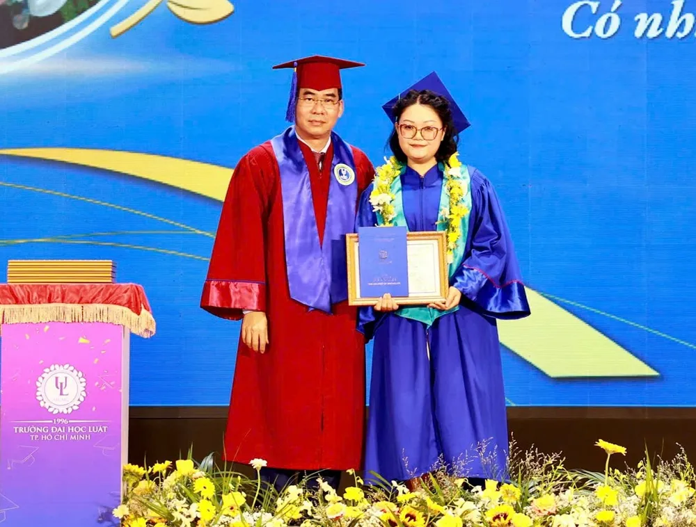 Tiến sĩ Lê Trường Sơn, Hiệu trưởng Trường ĐH Luật TP.HCM trao khen thưởng cho tân cử nhân Võ Nguyễn Anh Thư. truong-dh-luat-tphcm-le-tot-nghiep (3).jpg