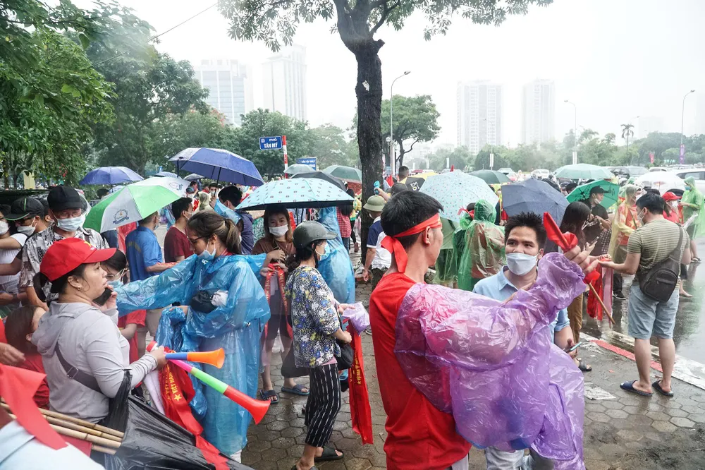 Trời đổ mưa nặng hạt, nhưng nhiều người hâm mộ đã đến khu vực lối vào của Sân vận động Mỹ Đình từ đầu giờ chiều, trang bị áo mưa, ô... để chuẩn bị bước vào bên trong.