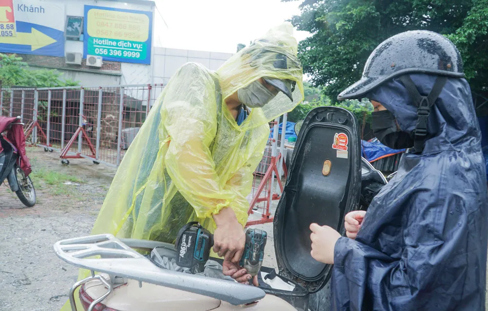 Dịch vụ sửa chữa xe máy được lập tạm thời ngay lề đường nơi có khu vực ngập úng để phục vụ người dân.