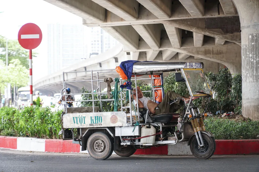 Nhiều tài xế xe ba bánh lựa chọn đỗ dưới gầm đường Vành đai 3 trên cao để chợp mắt giữa trưa nắng, tại đây nhiệt độ chênh lệch so với bên ngoài đến gần 10 độ C.