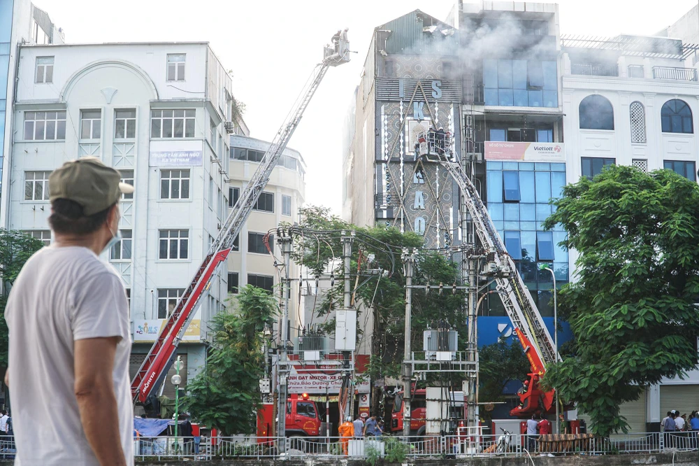 Nhiều người dân đứng bên bờ sông Tô Lịch theo dõi lực lượng chức năng chữa cháy.