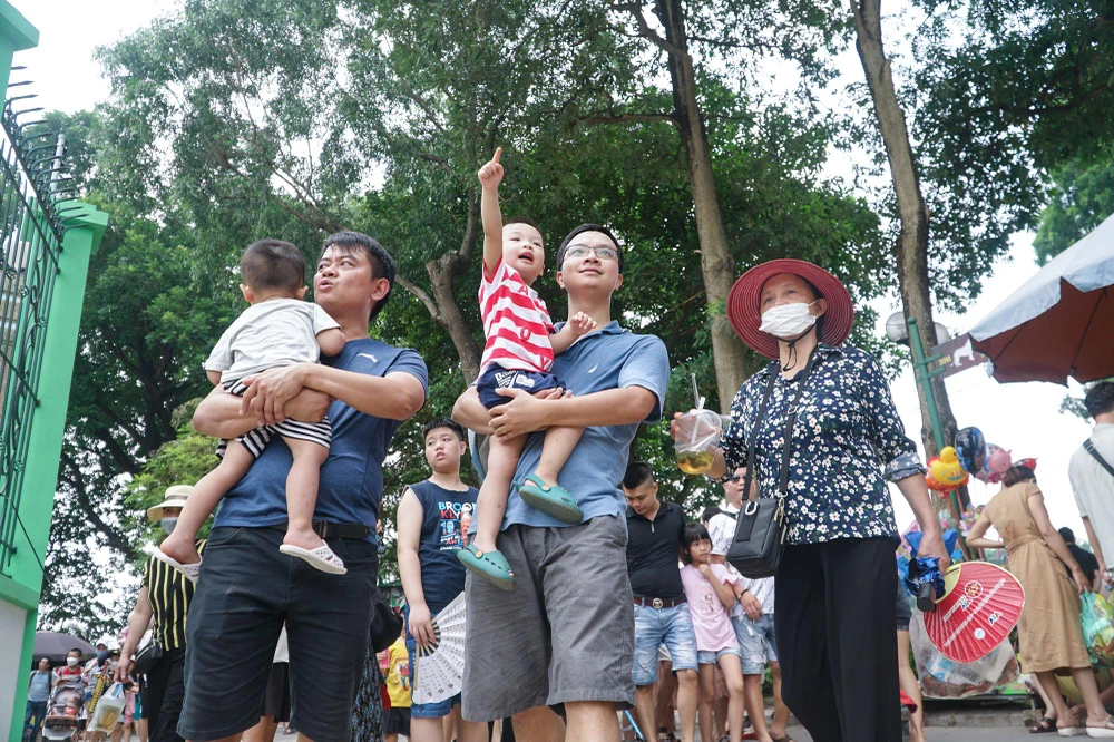 Hàng nghìn người dân tấp nập, bồng bế con nhỏ ra vào khuôn viên khu vui chơi ở Công viên Thủ Lệ.