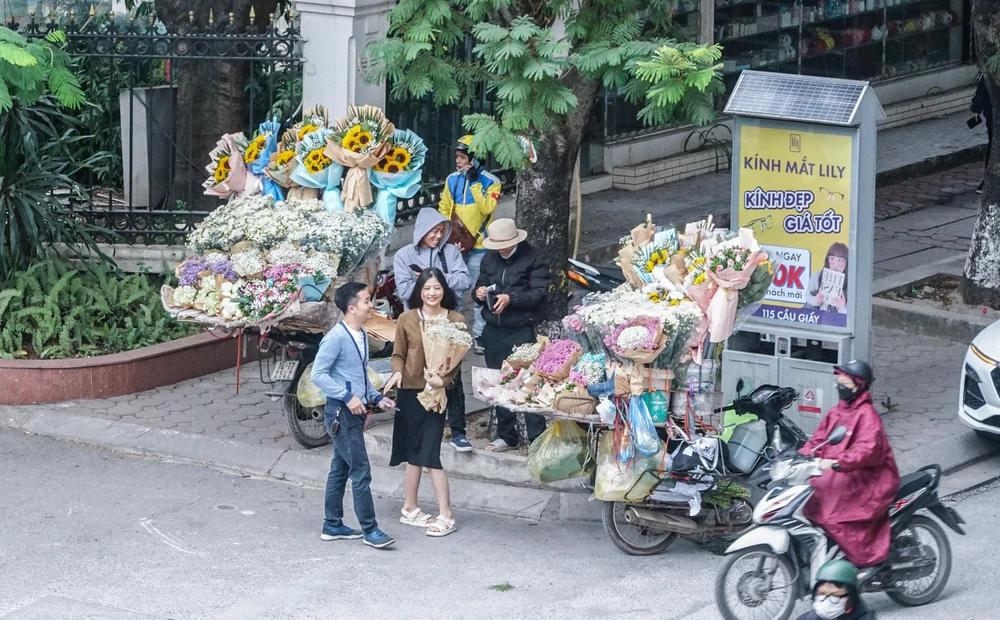 Sáng sớm, những xe hàng hoa trước cổng Trường ĐH Quốc gia Hà Nội khá đắt khách. Bất chấp giá lạnh, nhiều người vẫn tới đây, cùng người thân lựa những đóa hoa tươi thắm nhất.