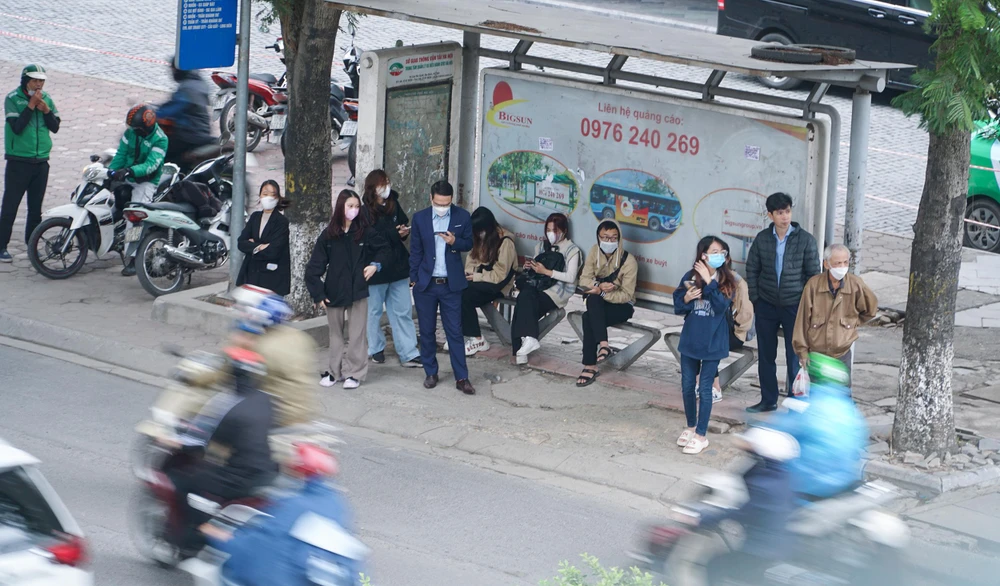 Trên đường Xuân Thủy, nhiều người dân co ro người đứng người ngồi để chờ xe buýt.