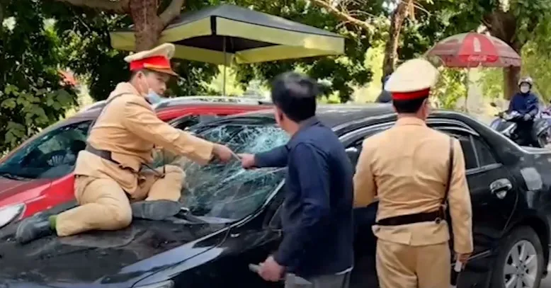 Hình ảnh CSGT bị hất văng lên nắp capo. Ảnh cắt từ clip. Hình ảnh CSGT bị hất văng lên nắp capo. Ảnh cắt từ clip.