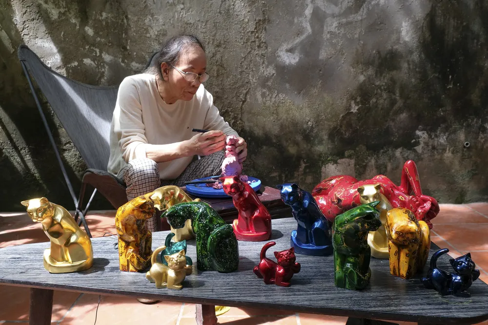 Để phục vụ nhu cầu thị trường Tết Nguyên đán Quý Mão 2023, Nhà điêu khắc Vũ Dũng đã dày công thiết kế bộ linh vật &quot;gia đình mèo&quot; và phủ chất liệu sơn mài.