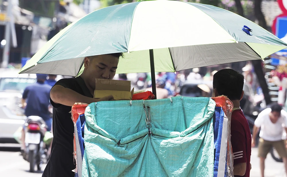 Với nền nhiệt độ ngoài trời cao, các shipper đã phải lắp ô che nắng khi di chuyển trên đường.