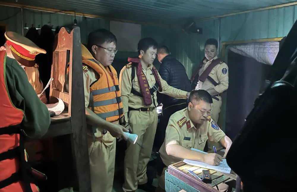 Lực lượng chức năng lập biên bản với chủ tàu hút cát trái phép trên sông Hồng. Ảnh CA