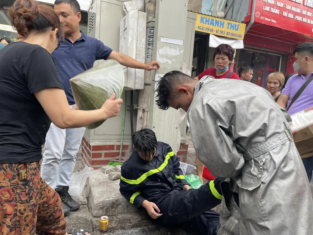 Một chiến sĩ cảnh sát PCCC kiệt sức được đồng đội và người dân hỗ trợ. Ảnh CTV Một chiến sĩ cảnh sát PCCC kiệt sức được đồng đội và người dân hỗ trợ. Ảnh CTV