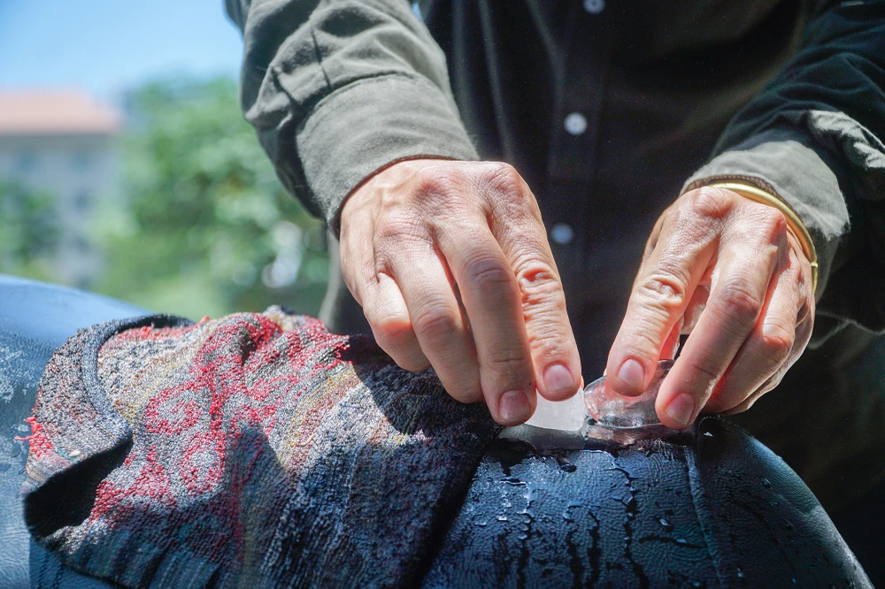 Do phơi nắng quá lâu, một người dân phải dùng khăn ướt, đá lạnh để làm mát yên xe mới có thể tiếp tục di chuyển.