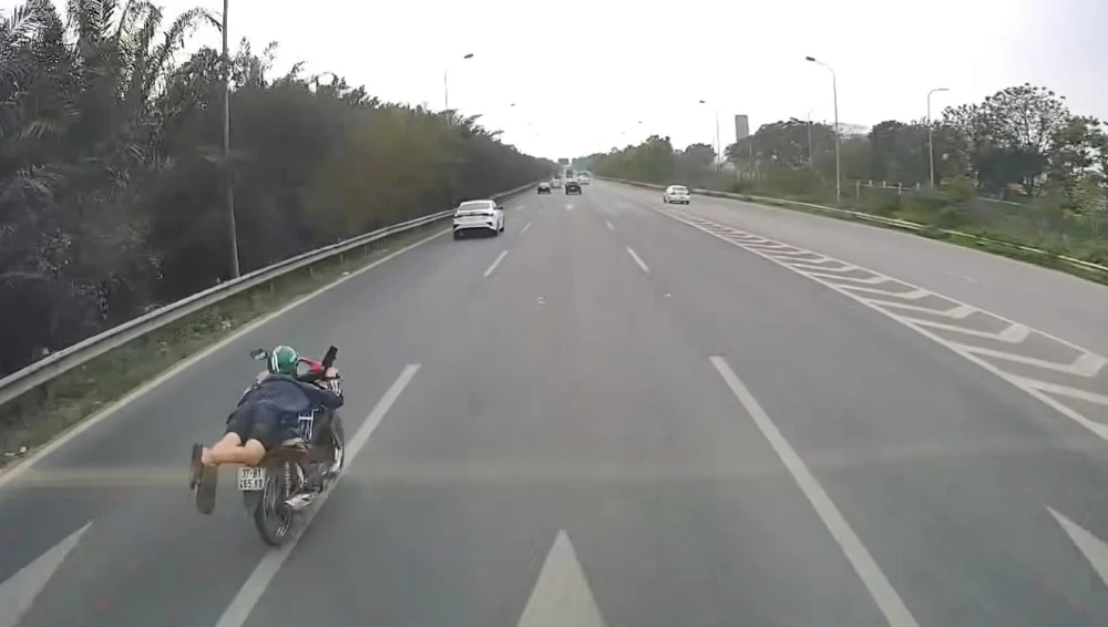 Nam thanh niên nằm trên yên xe máy vượt ô tô trên Đại lộ Thăng Long