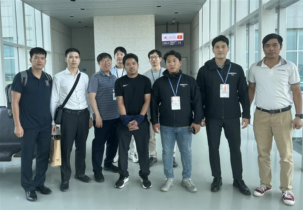 Interpol Hàn Quốc bàn giao cho Interpol Việt Nam bị can Nguyễn Văn Tấn (che hai tay đứng giữa) để dẫn giải từ Hàn Quốc về Việt Nam.Ảnh CA interpol-viet-nam.jpg