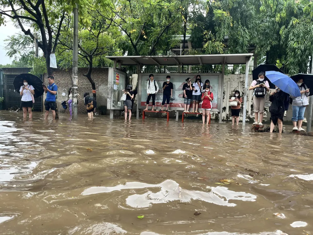 Tại một điểm buýt cách đó không xa, thay vì ngồi chờ xe, thì nhiều sinh viên lựa chọn phương án đứng do nước ngập.